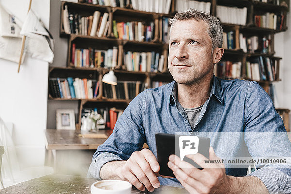 Erwachsener Mann sitzt im Café und liest E-Book