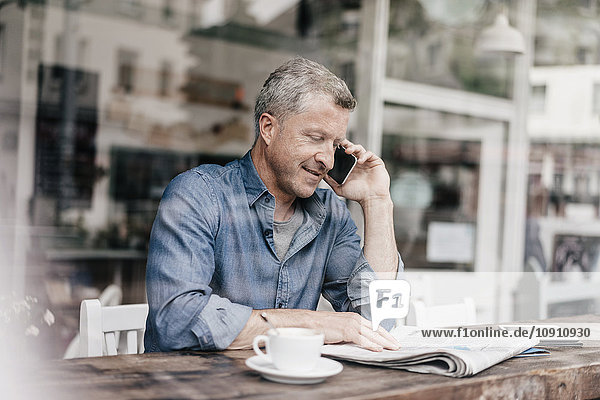 Mature man sitting in cafe talking on the phone