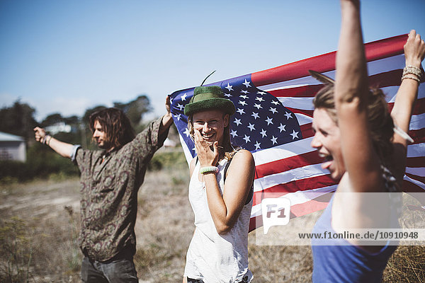 Three carefree hippies with US flag in the nature