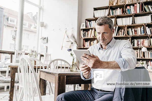 Geschäftsmann sitzend im Cafe mit digitalem Tablett