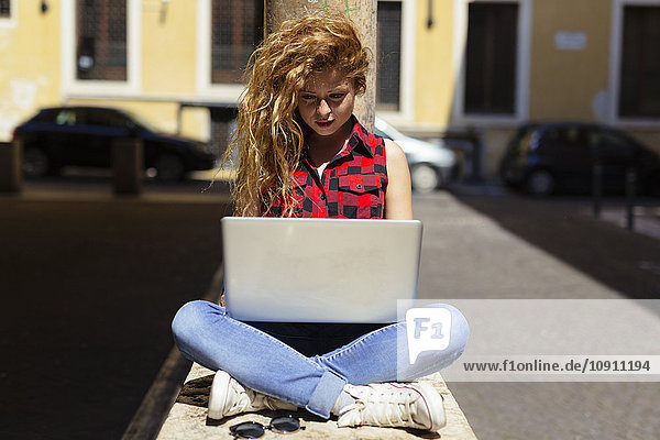 Italien  Verona  Frau im Freien sitzend mit Laptop
