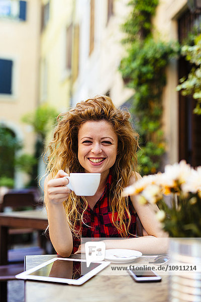 Porträt einer lächelnden Frau im Außencafé