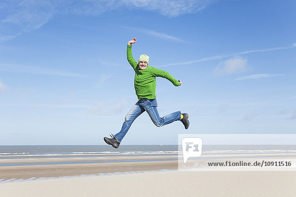 Enthusiastischer reifer Mann beim Springen am Strand