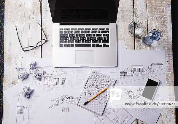 Schreibtisch eines Architekten mit Laptop und Skizzen