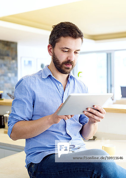 Man working in kitchen using digital tablet
