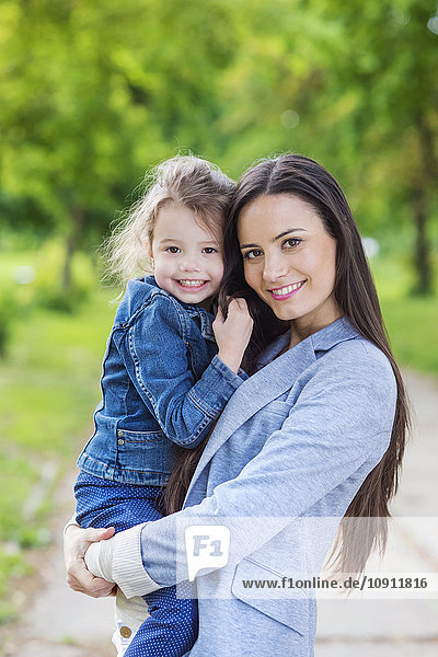 Portrait of mother holding daughter in park