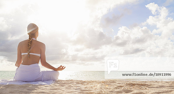 Dominikanische Rebublik  Junge Frau bei Yoga-Übungen mit Blick über den tropischen Strand