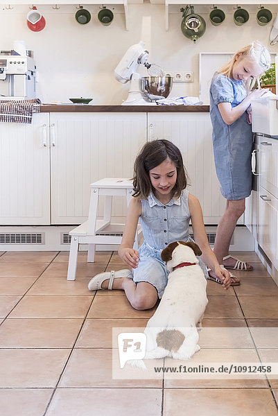 Zwei kleine Mädchen mit ihrem Hund in der Küche