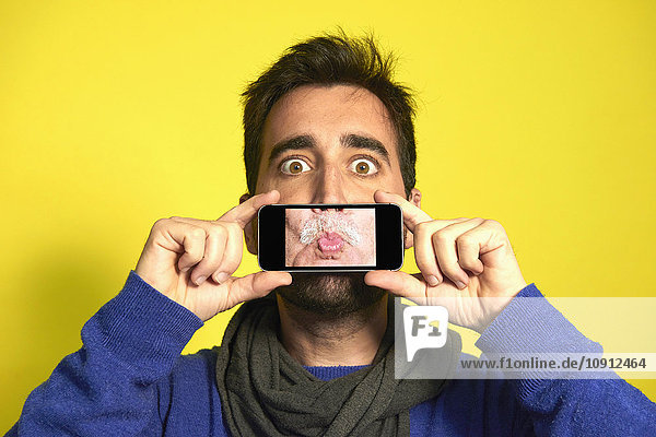 Porträt eines Mannes  der ein Smartphone hält  mit Fotografie des Schmolls eines anderen Mannes.