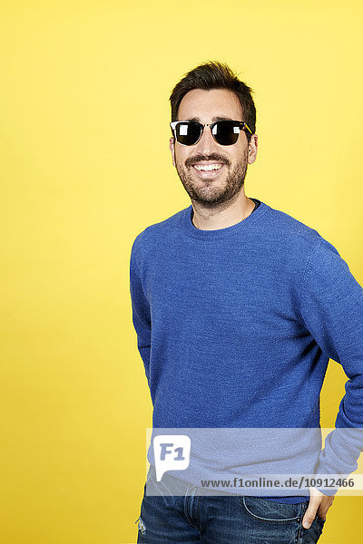 Porträt eines lächelnden Mannes mit Sonnenbrille vor gelbem Hintergrund