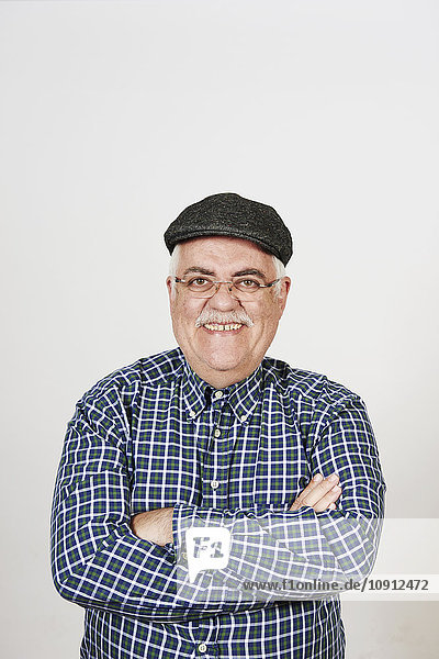 Porträt eines lächelnden älteren Mannes mit gekreuzten Armen vor weißem Hintergrund