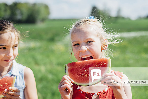 Two girls outdoors eating slices of watermelon