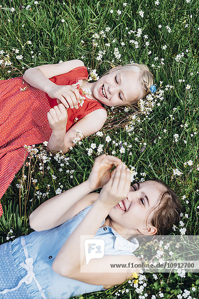 Two happy girls lying in flower meadow
