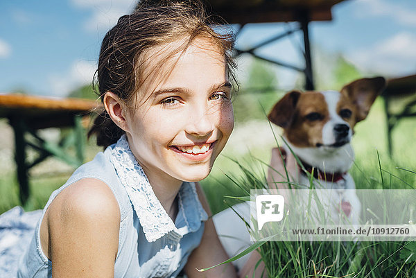 Portrait of smiling girl with dog in meadow