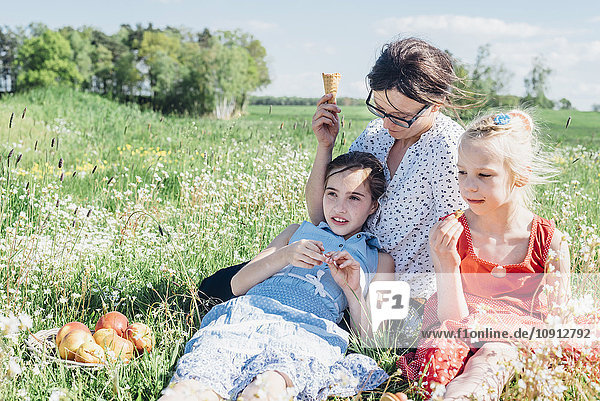 Mother and two girls relaxing in meadow