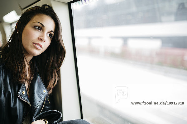 Junge Frau im Zug mit Blick aus dem Fenster