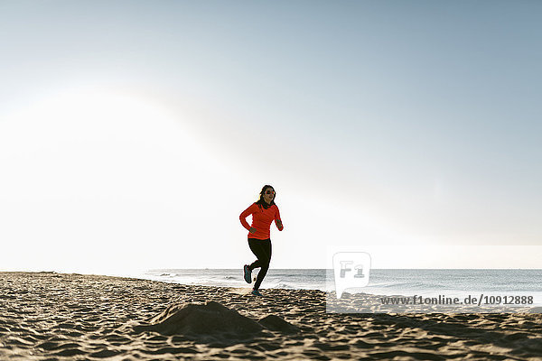 Frau beim Joggen am Strand am frühen Morgen