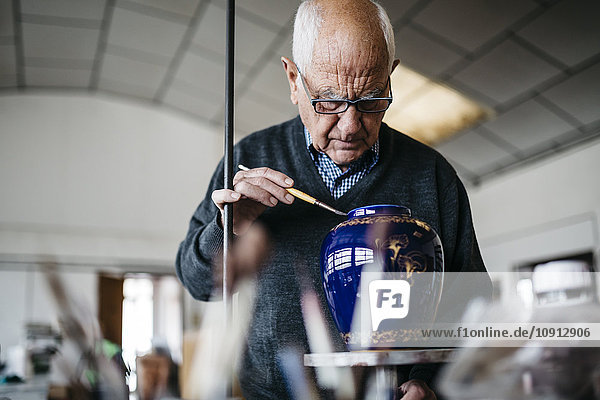 Senior Mann dekoriert Keramikvase in seiner Freizeit