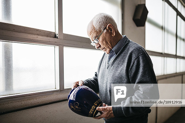 Älterer Mann beim Betrachten der Keramikvase
