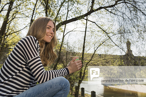 Smiling young woman outdoors with cup of coffee