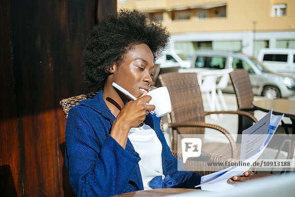 Junge Frau arbeitet und trinkt Kaffee in einem Straßencafé