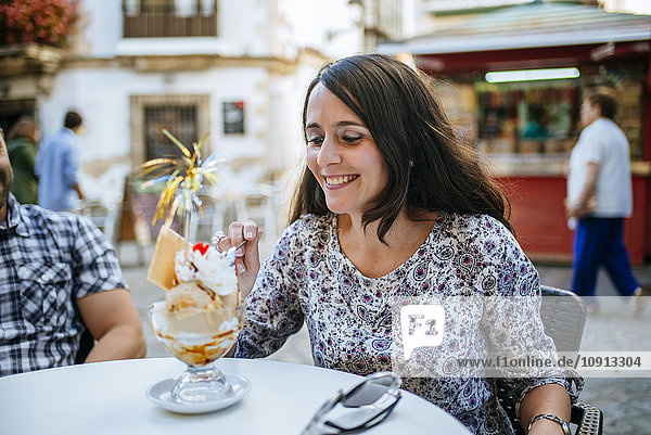 Frau isst Eis in einem Straßencafé