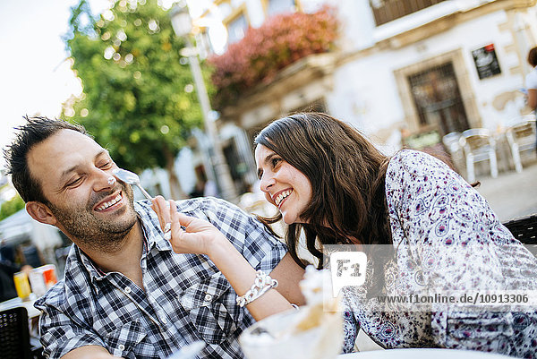 Ein Paar hat Spaß beim Eis essen in einem Straßencafé.