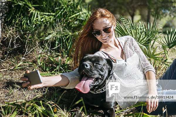 Lächelnde junge Frau  die einen Selfie mit ihrem Hund nimmt.