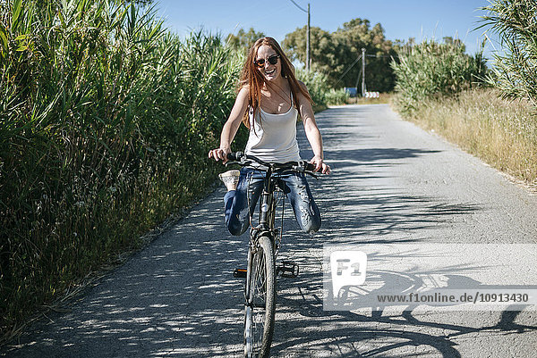 Glückliche junge Frau beim Radfahren auf dem Landweg