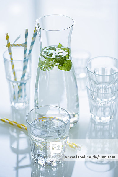 Glasflasche Wasser mit Zitronenmelisse und verschiedenen Gläsern