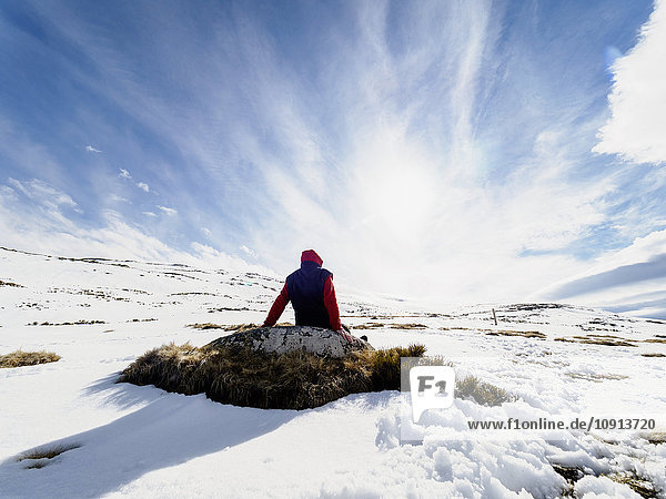 Spanien  Sierra de Gredos  Wanderer auf Felsen im Schnee sitzend