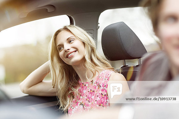 Porträt einer lächelnden blonden Frau auf dem Beifahrersitz im Auto