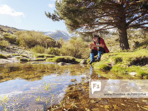 Spanien  Sierra de Gredos  Wanderer am See beim Lesen eines Buches