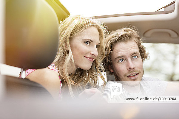 Porträt eines jungen Paares im Auto  das etwas beobachtet.