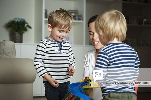 Two little boys playing at home with their mother