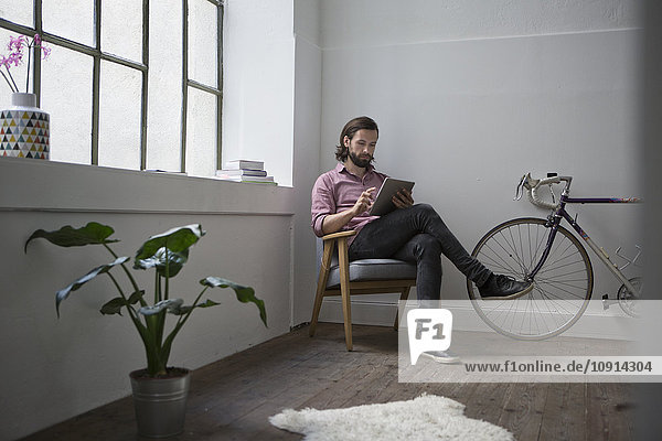 Mann im Stuhl sitzend mit digitalem Tablett