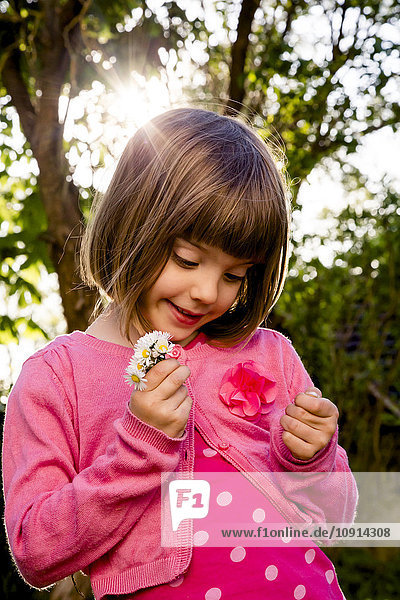 Porträt eines kleinen Mädchens mit Gänseblümchen in den Händen