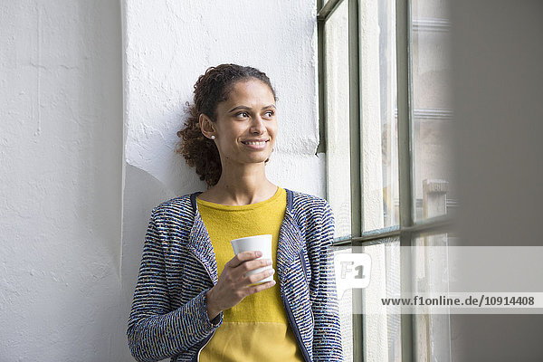 Junge Frau am Fenster mit einer Tasse Kaffee