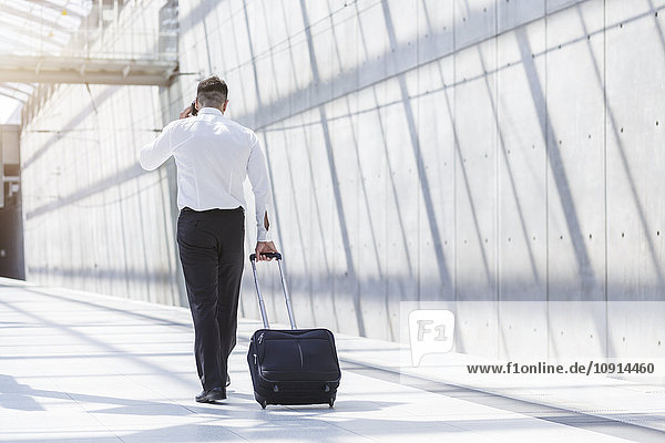 Businessman with luggage and cell phone on the move