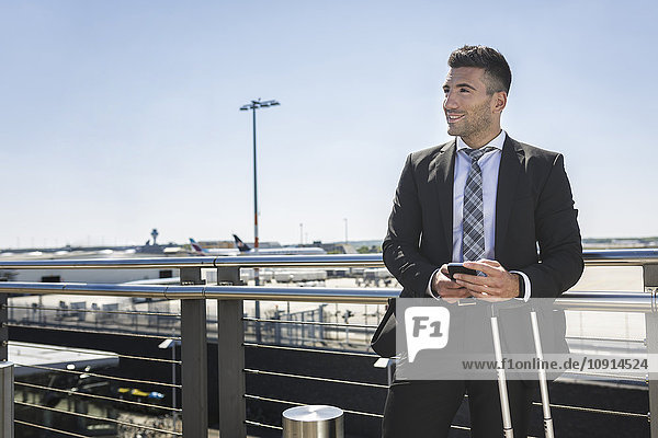 Businessman with luggage and cell phone at the airport