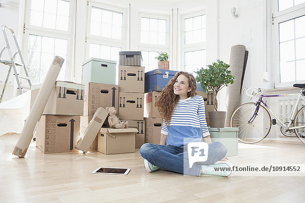 Woman surrounded by cardboard boxes sitting on floor