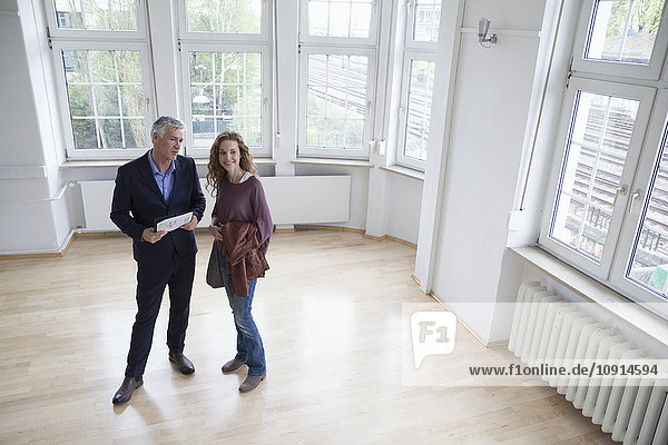 Real estate agent talking to client in empty apartment
