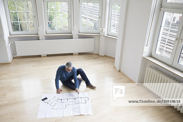 Man looking at construction plan in empty apartment