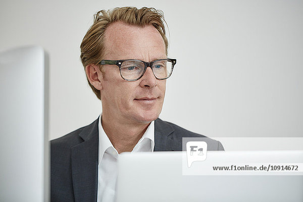 Portrait of businessman wearing glasses looking at computer