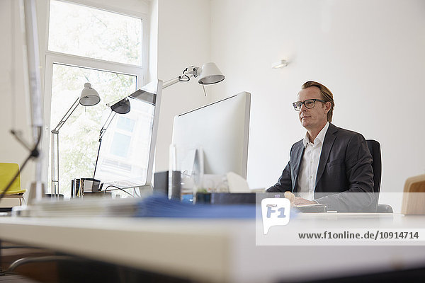 Businessman sitting at desk in an office working with computer