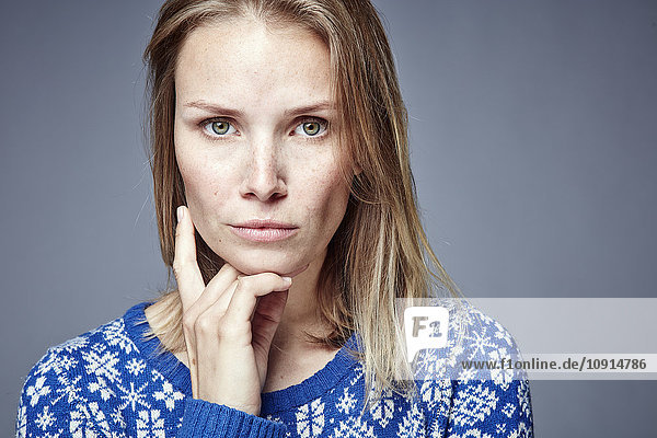 Porträt einer ernsthaften blonden Frau mit Hand am Kinn