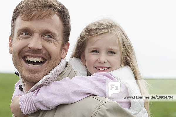 Happy father carrying daughter piggyback outdoors