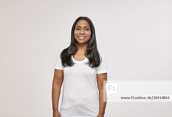 Porträt einer selbstbewussten Frau mit schwarzen Haaren in weißem T-Shirt