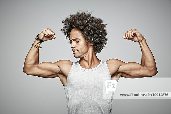 Porträt eines Mannes mit Afro  der seine Muskeln beugt.