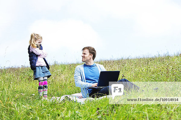 Vater und Tochter sitzen auf der Wiese  Laptop  Vater sucht Tochter